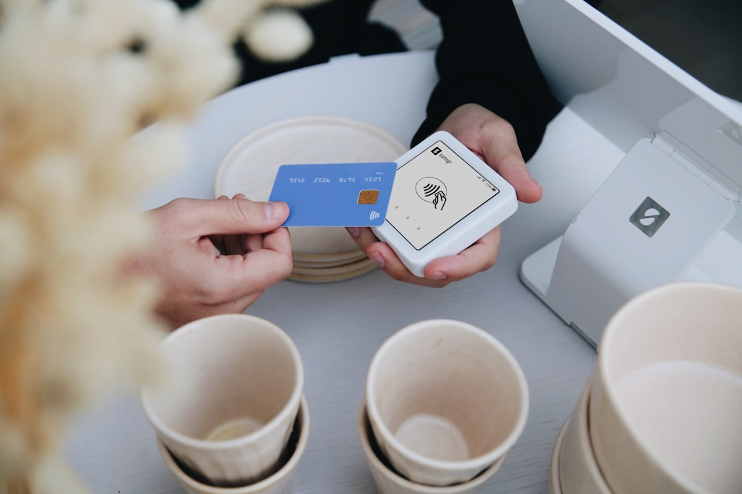 A customer taps a blue credit card on the SumUp Solo card reader. This image captures the simplicity and speed of contactless payments in small, stylish businesses.